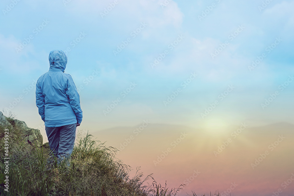 Woman standing over cliff at sunrise