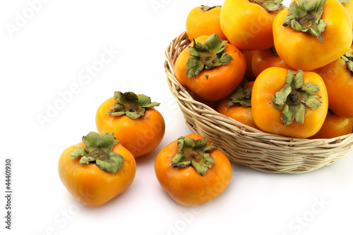 persimmon fruits in woon basket on white background