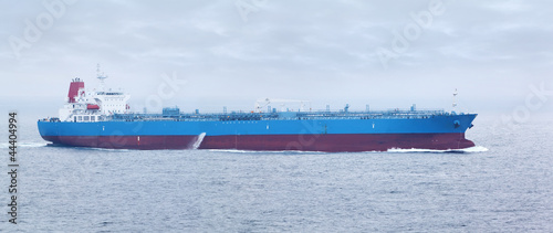 Large cargo ship with red and blue boards floats in open ocean photo