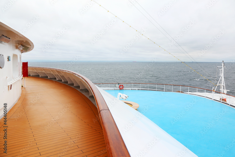 Snout with railing of large cruise ship. View from wooden deck.