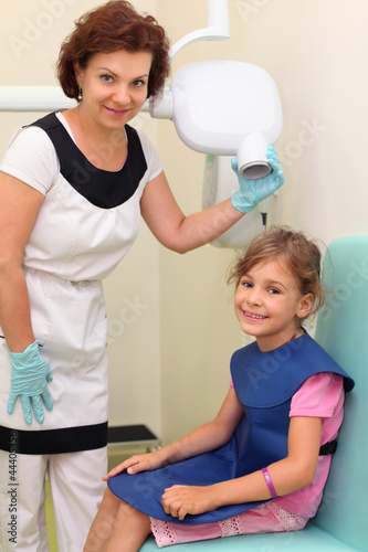 Dentist prepares girl wearing in protective lead apron