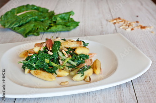 fresh salad with chard noodles and pine nuts on wooden table