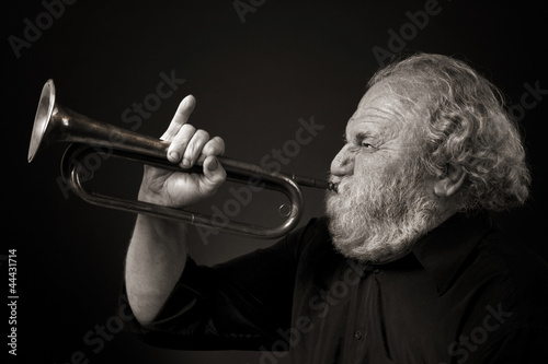 Bild auf Leinwand Bearded old man blowing a bugle with gusto