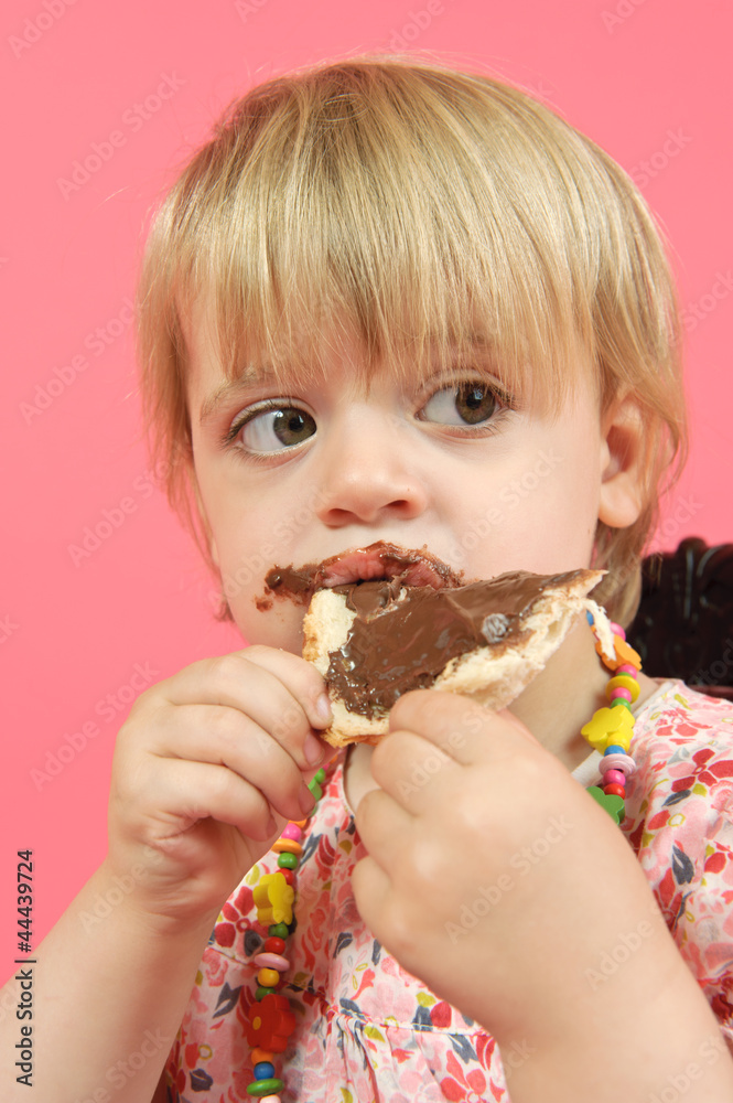 Mädchen isst ein Brot mit Schokoladencreme Mädchen isst ein Brot mit Schokoladencreme