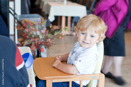 Adorable baby boy sitting on child chair in restaurant
