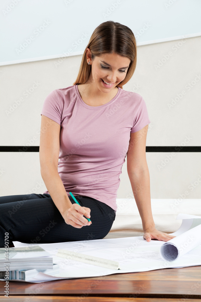 Obraz premium Female Architect Working On Blueprint