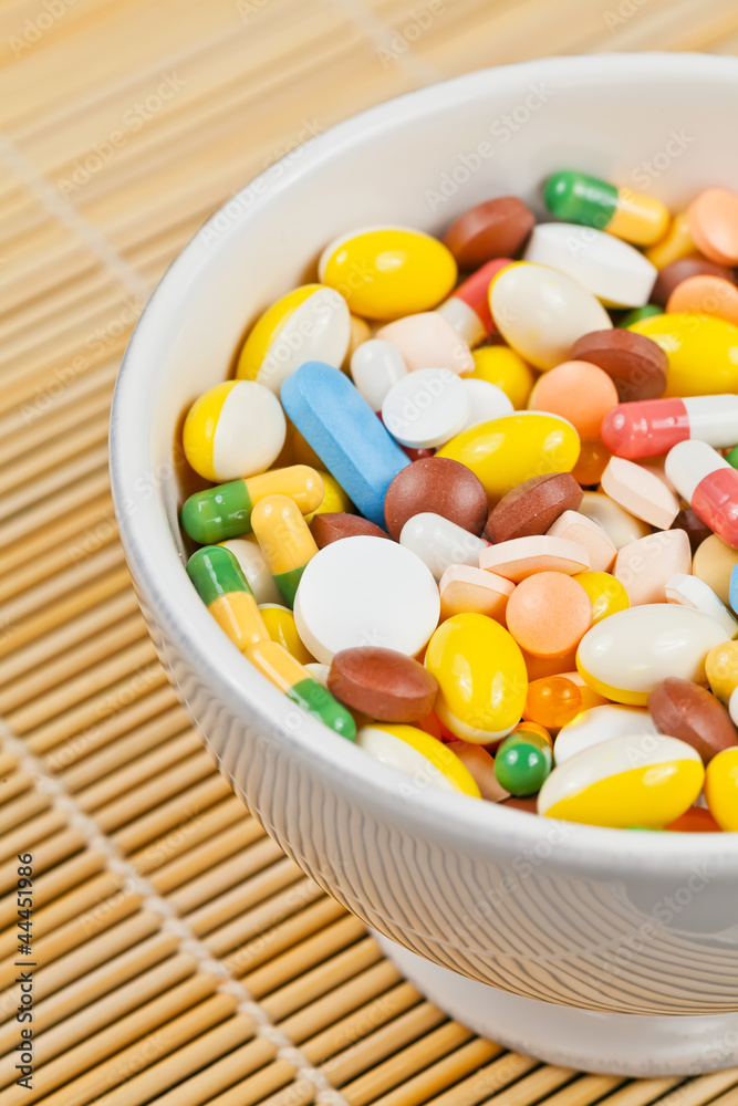 White cup filled with medicine pills and capsules White cup filled with medicine pills and capsules