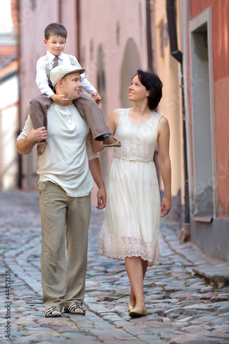 Happy young family walking in city street