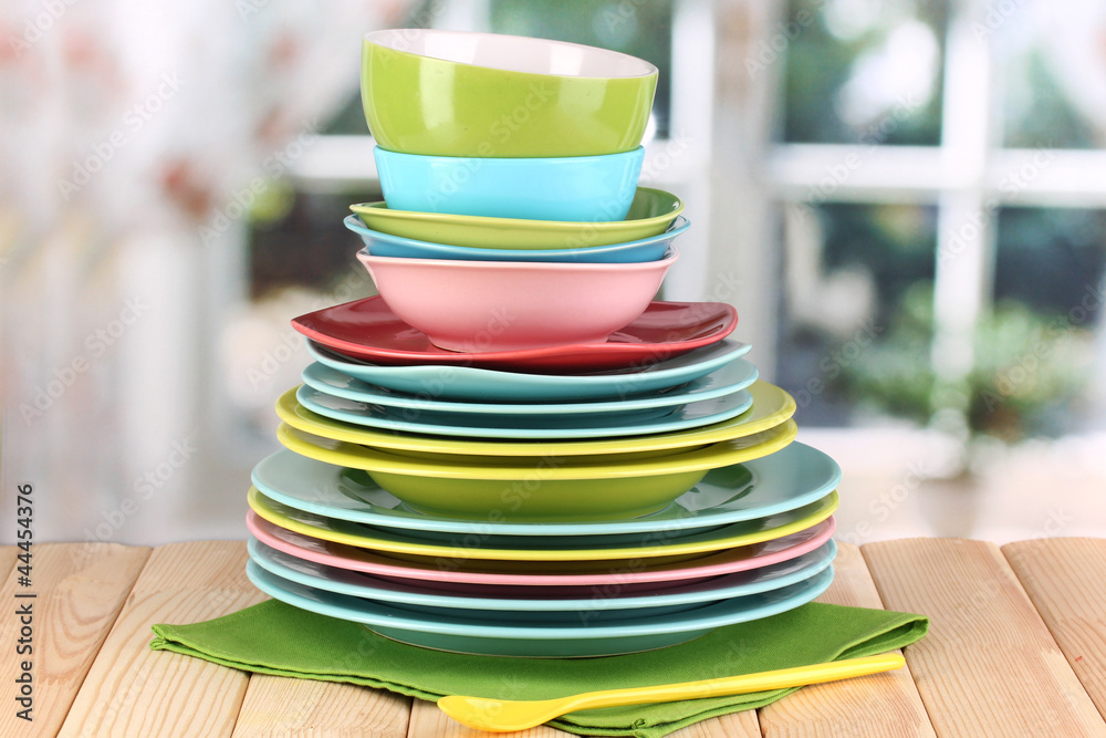 Colorful tableware on wooden table on window background