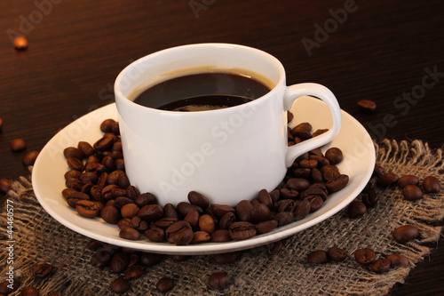 Cup of coffee close-up on wooden table on brown background
