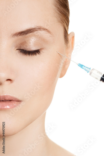 Beautiful woman gets an injection in her face isolated on white