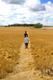 two boys walking through a wheat field