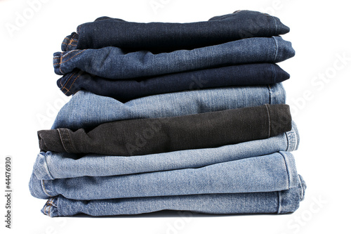Stack of folded blue jeans on a white background