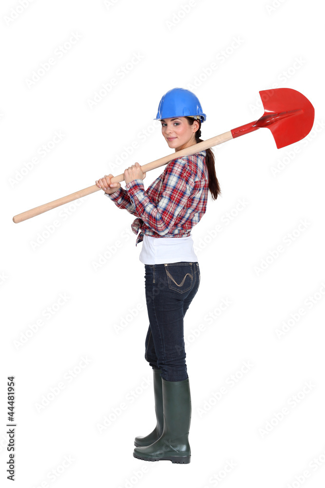Female manual worker carrying shovel Female manual worker carrying shovel