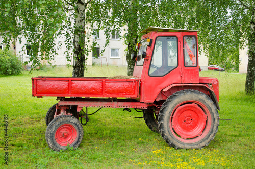 Retro red agricultural tractor under birch trees