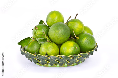 Green sweet oranges in coconut leaf on white background