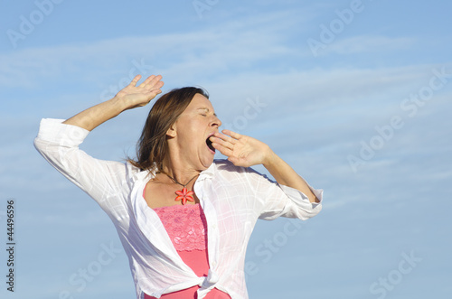 Tired woman yawning sky background