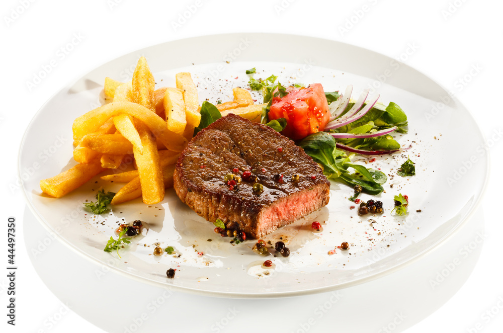 Grilled steaks, French fries and vegetables Grilled steaks, French fries and vegetables