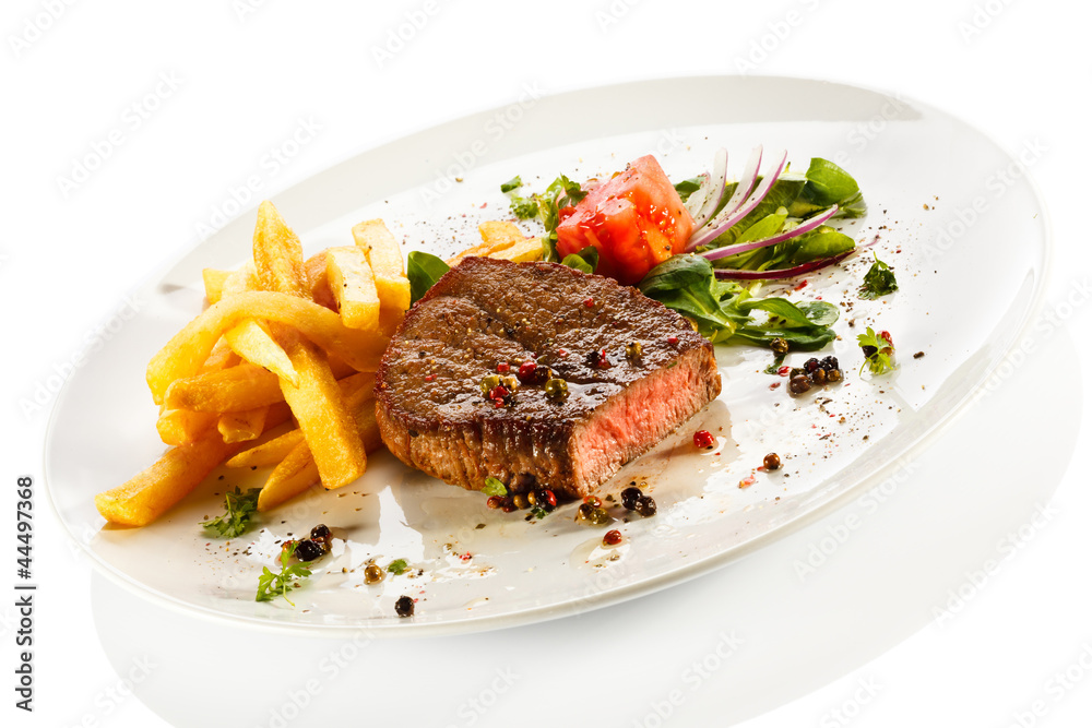 Grilled steaks, French fries and vegetables Grilled steaks, French fries and vegetables