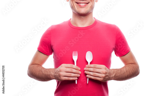 Portrait of a smiling boy holding plastic spoon and fork