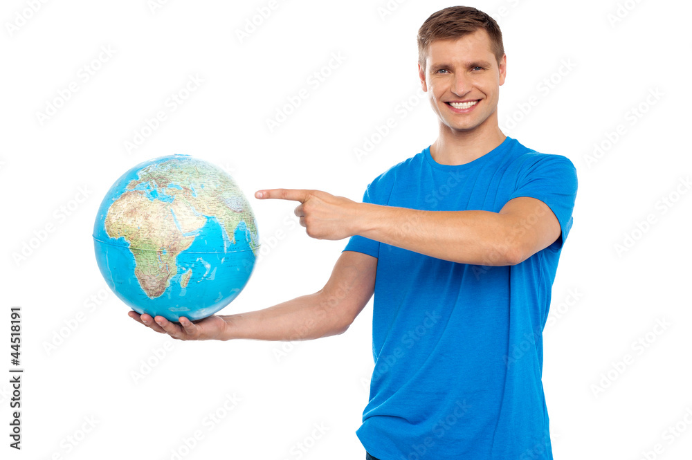 Handsome young caucasian pointing at globe Handsome young caucasian pointing at globe