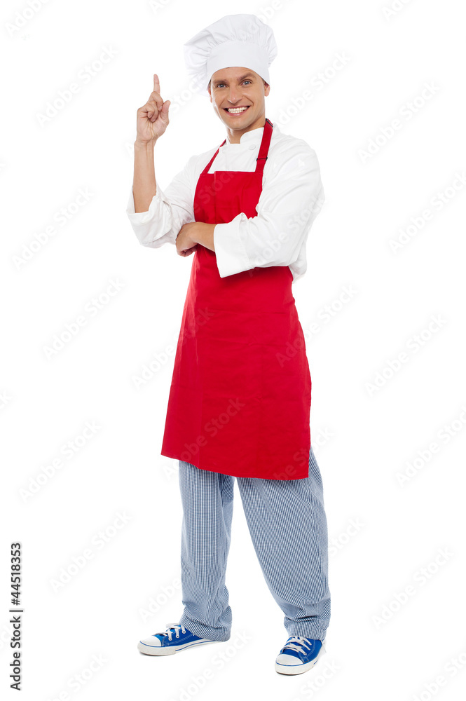 Young smart chef pointing index finger upwards Young smart chef pointing index finger upwards