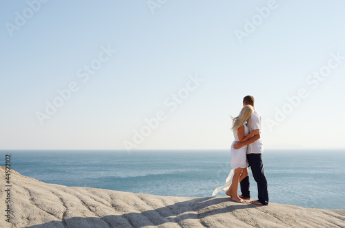 Girl and boy standing arm in arm near the sea