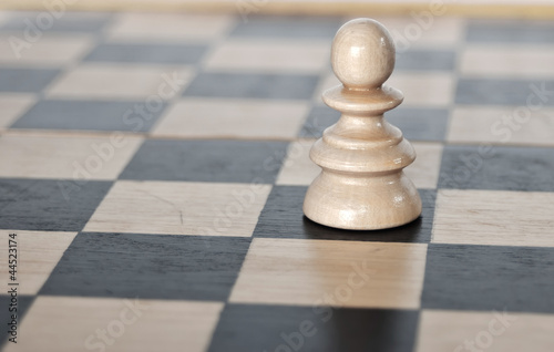 lonely chess pawn on board background