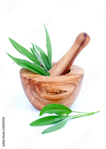 wooden mortar with green leaves of sage, on white background