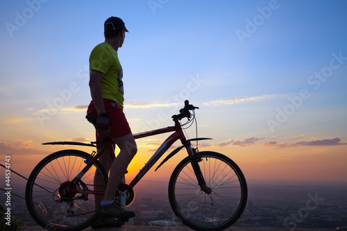 young man with a bicycle at sunset.