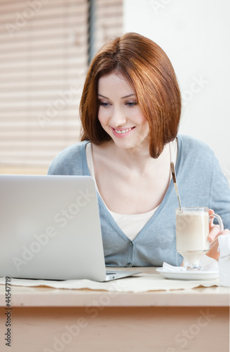 Woman is working on the personal computer at the coffee house