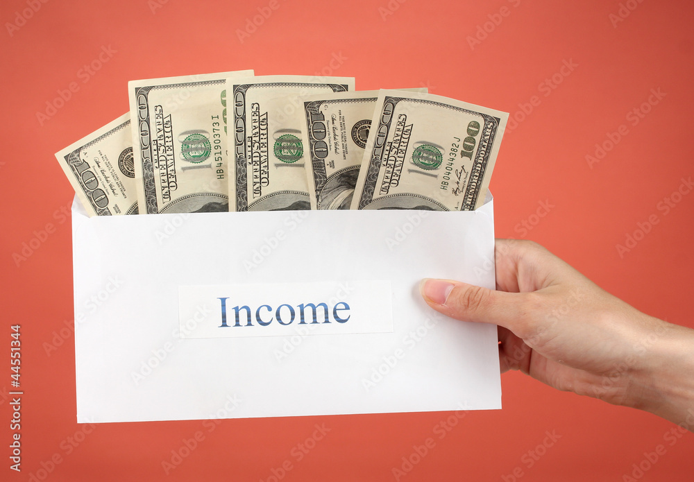 Woman's hand holding an envelope with money on red background Woman's hand holding an envelope with money on red background