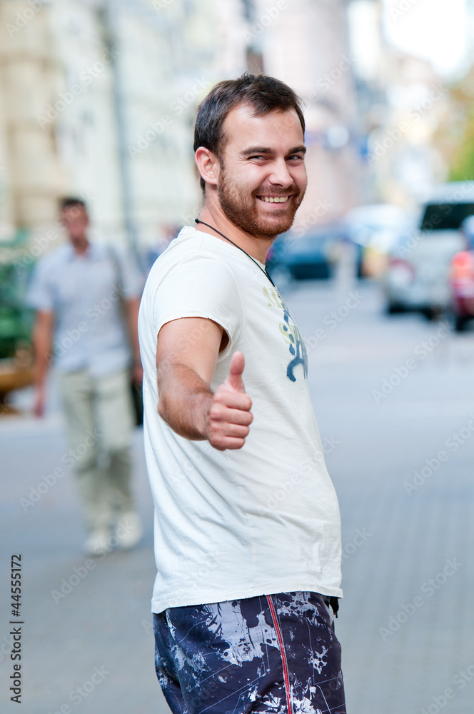 Portrait of cheerful young guy. Shows thumb up. Cool.