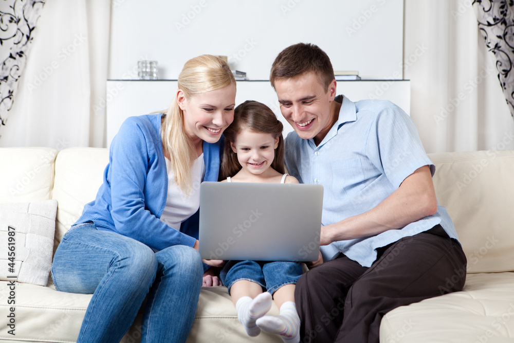 Happy family of three make purchases through the internet Happy family of three make purchases through the internet