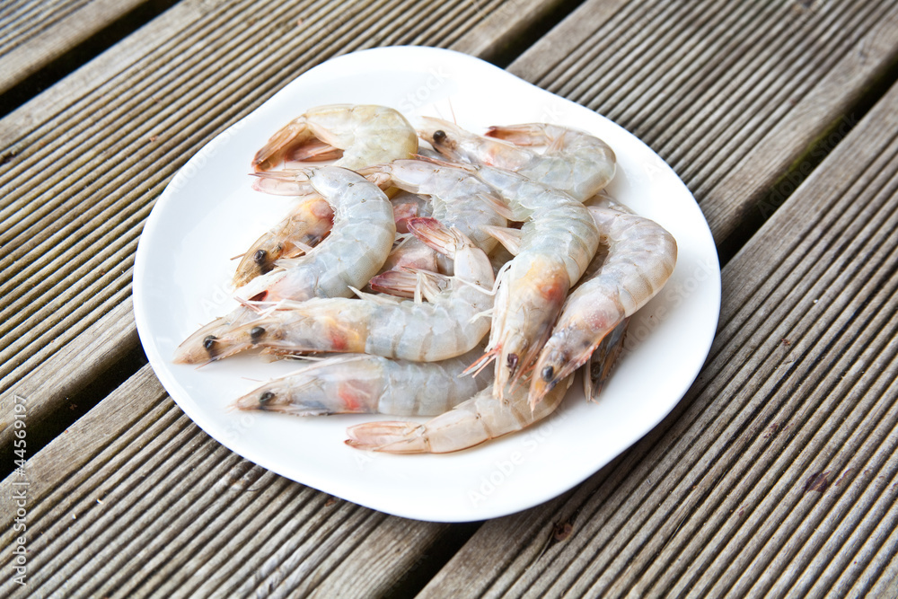 Uncooked tiger prawns on a white plate. Uncooked tiger prawns on a white plate.