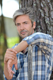 Portrait of middle-aged man standing against tree