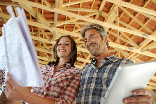 Cheerful couple standing inside house under construction