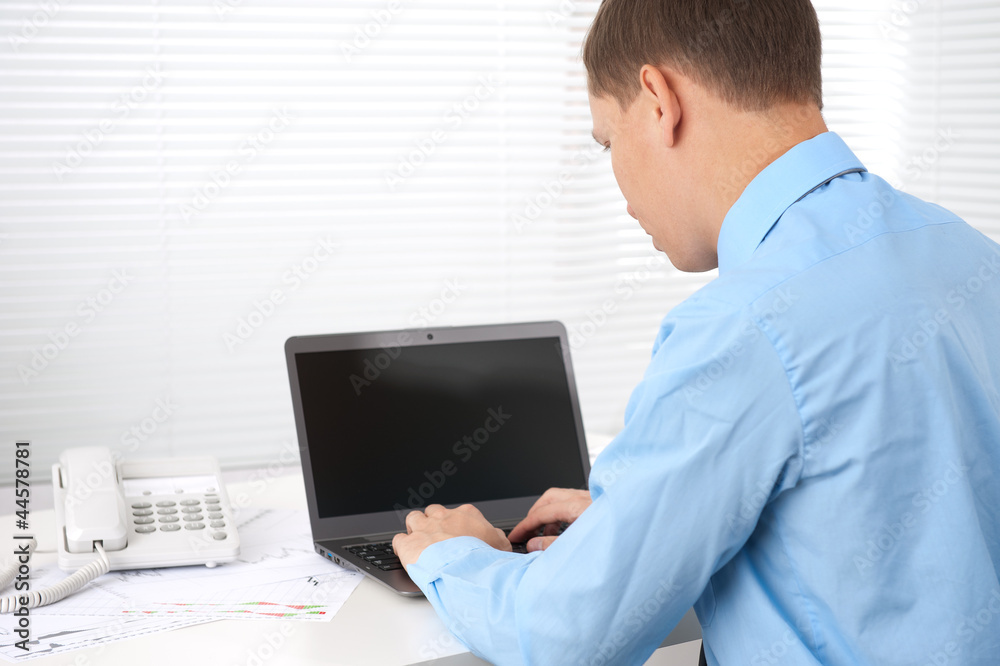 Rear view of a young business man working of a laptop Rear view of a young business man working of a laptop
