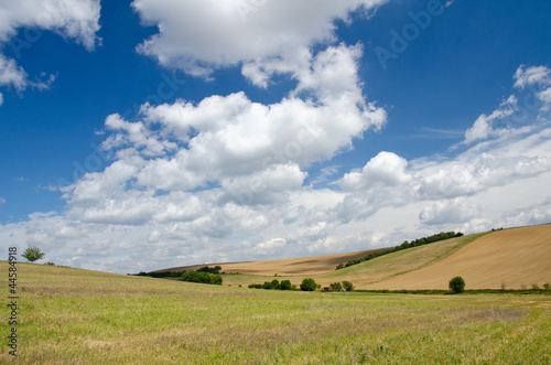Summer landscape with hills, fields and clouds