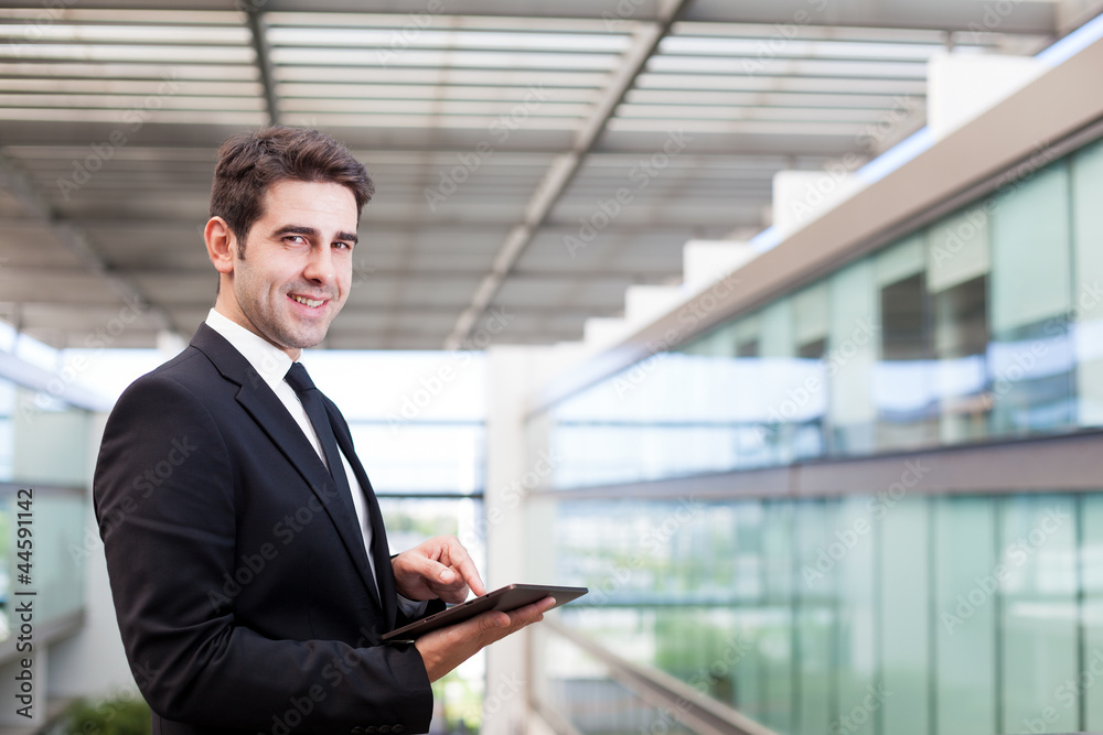 Smiling young businessman using his digital tablet at the office Smiling young businessman using his digital tablet at the office