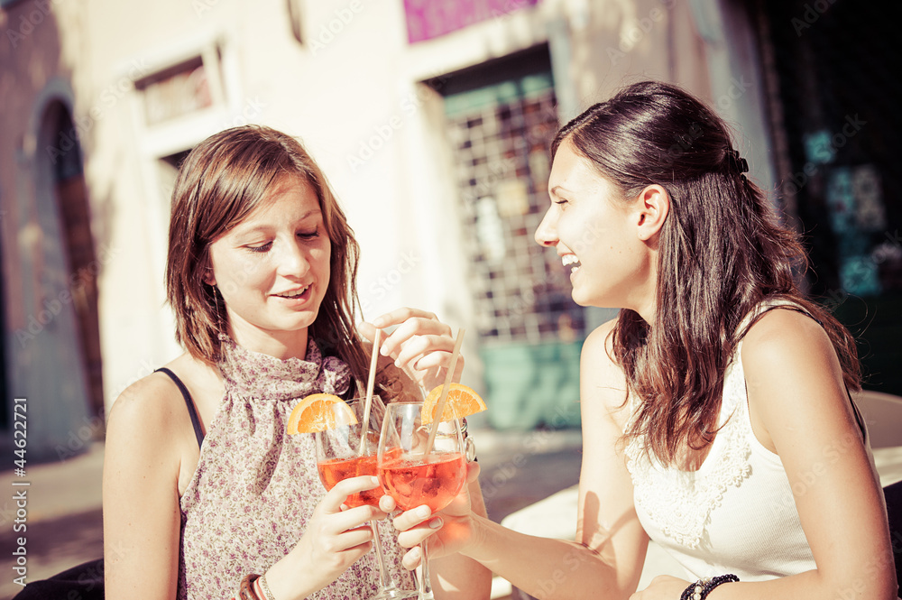 Two Young Women Cheering with Cold Drinks