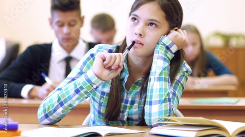 Beautiful pensive student writing lecture and thinking