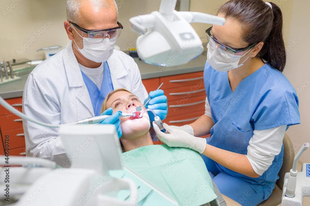 Dentist with nurse doing procedure on patient