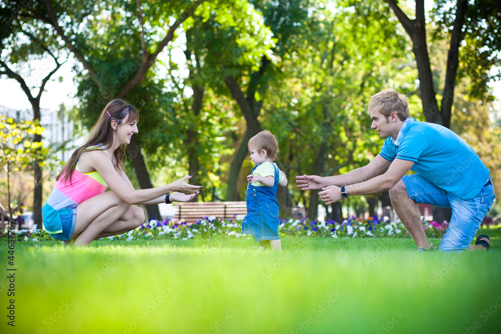 Fototapeta premium happy parents with a baby in a greenl summer park