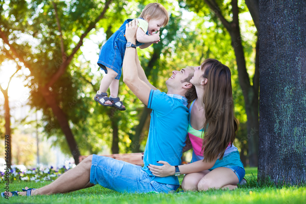 Fototapeta premium happy parents with a baby in a greenl summer park