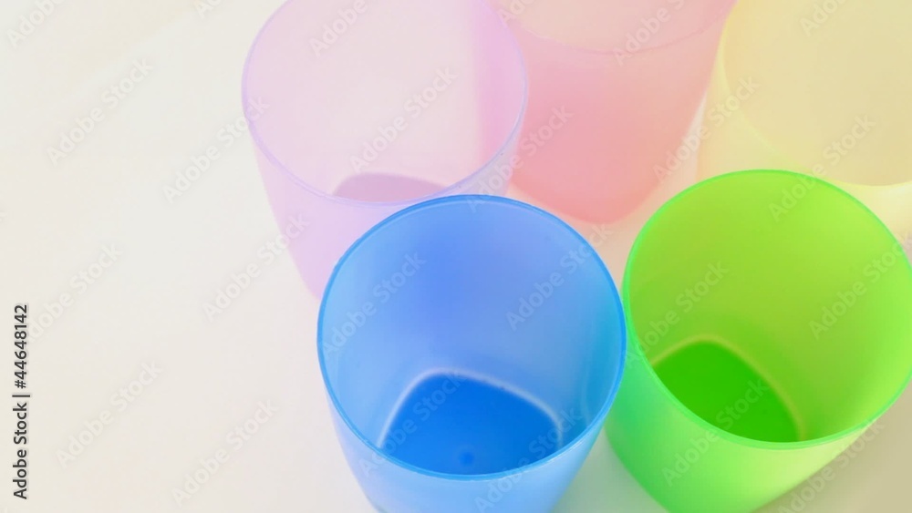 Five multi-colored glass glasses rotates on white background