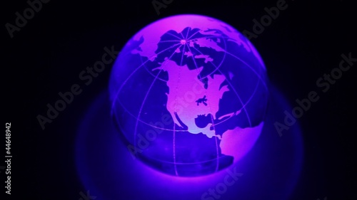 Sphere spins with world map on it and color illumination photo