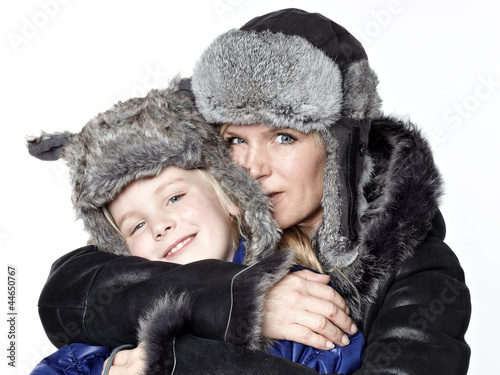 Mother and daughter in warm winter coats huggle together photo