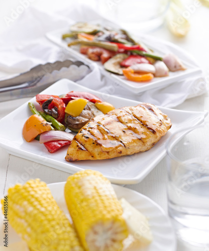 bbq grilled chicken and vegetables with corn on the cob.