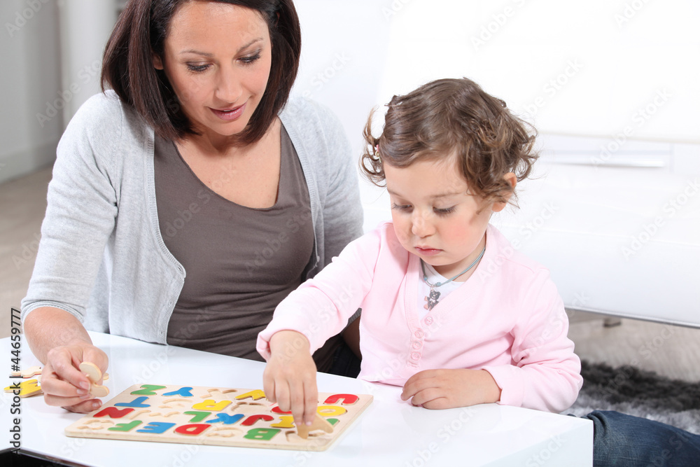 Mother and daughter completing a letter puzzle Mother and daughter completing a letter puzzle